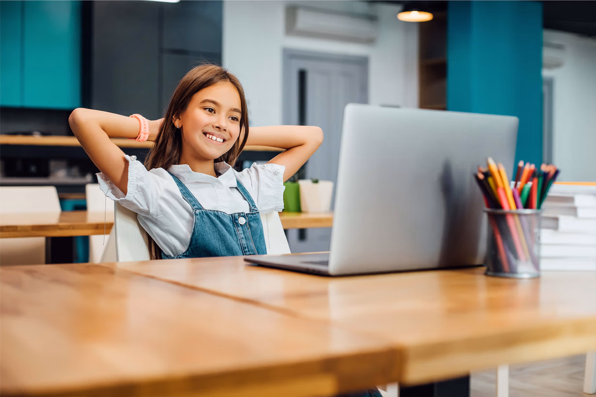 Un enfant devant un ordinateur concentré et heureux.