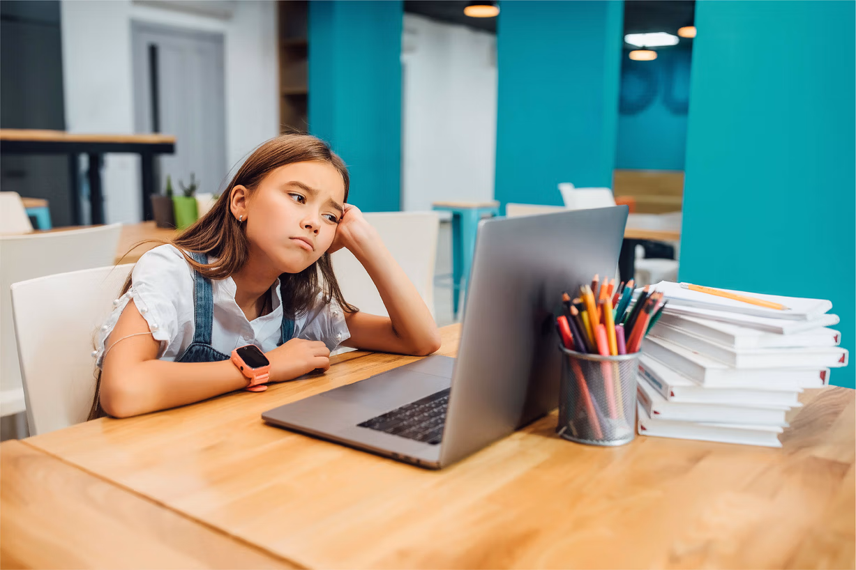 Un enfant devant un ordinateur qui n'est pas concentré et pas content.