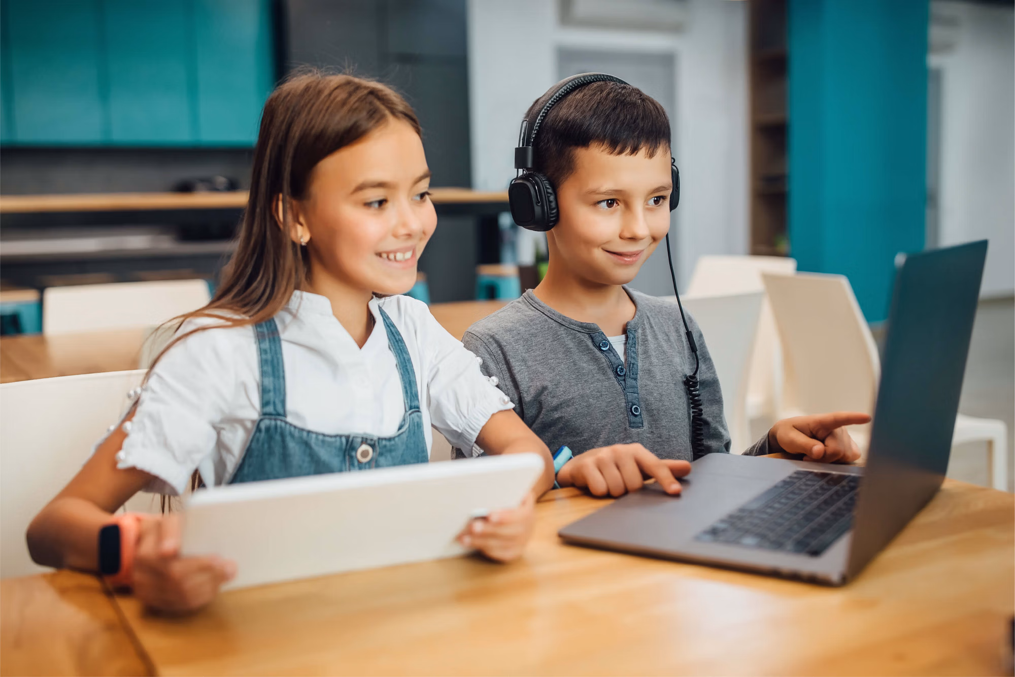 Deux enfants avec des ordinateurs sur une table.